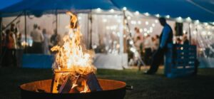 Atmospheric winter parties setup with warm lighting, fire bowls and guests gathering outdoors in January