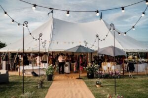 Marquee wedding with guests enjoying the evening surrounded by marquee accessories like festoon lighting and marquee furniture.