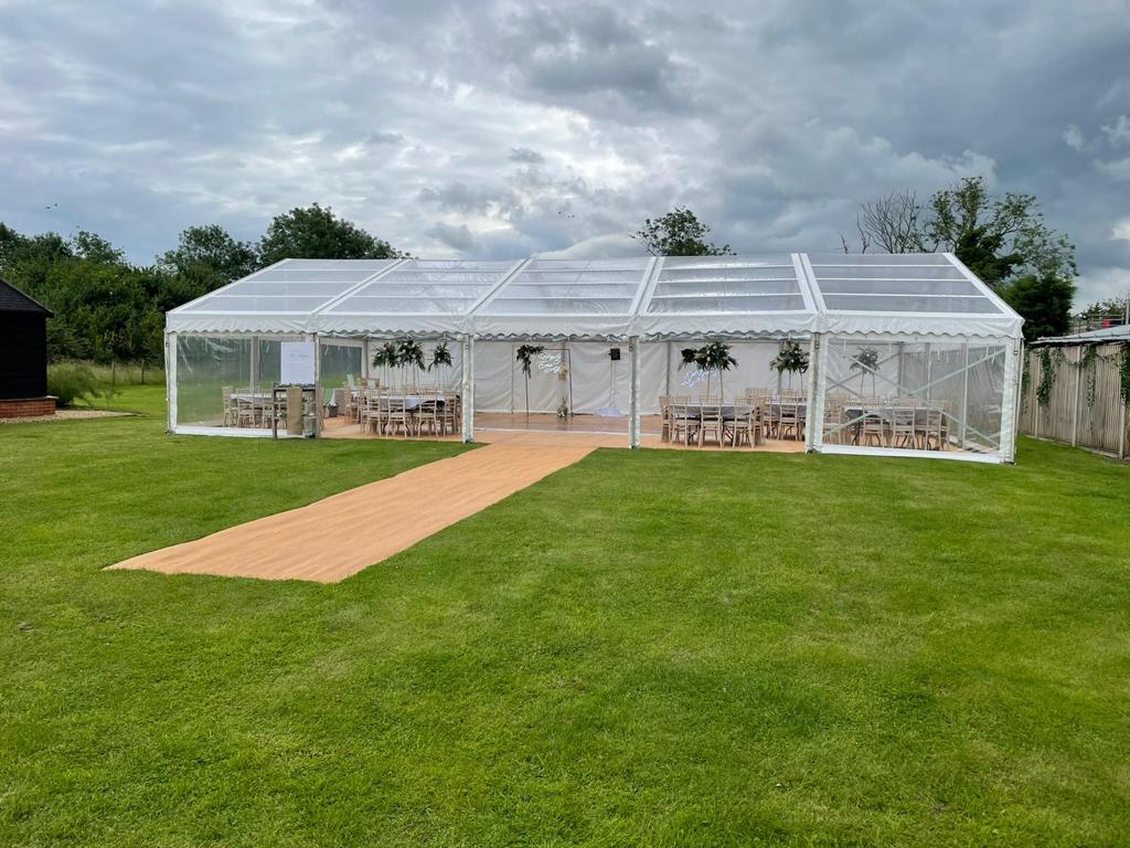 Planning an event on grass? White marquee with clear sides on grass lawn.